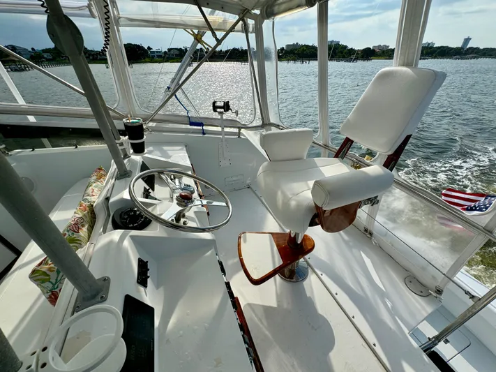 Reel Amnesia Yacht Photos Pics 1984 Hatteras 36 Convertible boat cockpit with steering wheel and captain's chair on open water.