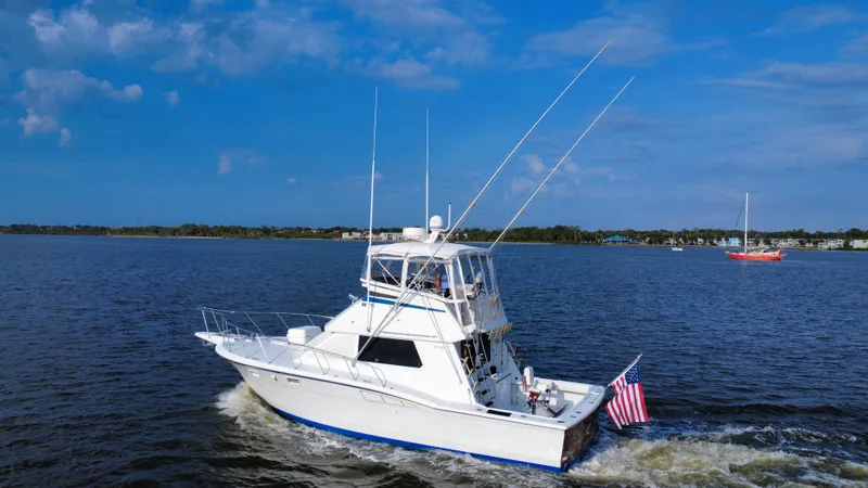 Reel Amnesia Yacht Photos Pics 1984 Hatteras 36 Convertible yacht cruising on a sunny day with American flag.