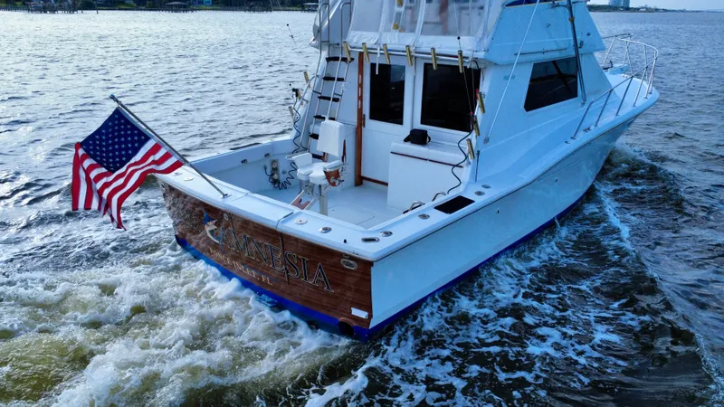 Reel Amnesia Yacht Photos Pics 1984 Hatteras 36 Convertible yacht cruising with American flag on water.