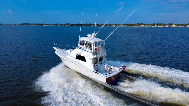 Reel Amnesia Yacht Photos Pics 1984 Hatteras 36 Convertible yacht cruising on open water, creating a wake.