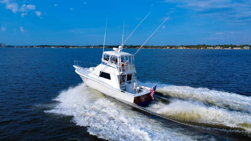 Reel Amnesia Yacht Photos Pics 1984 Hatteras 36 Convertible yacht cruising on open water under clear blue skies.