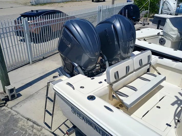 270-912 Yacht Photos Pics 2024 ShearWater 270 Carolina SS Open Bow with dual outboard motors, docked near a fence.