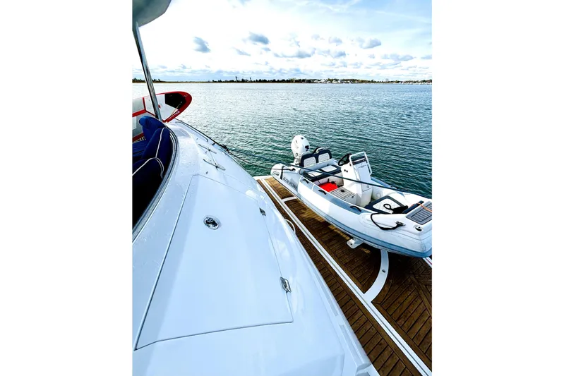  Yacht Photos Pics Sunseeker 75 Sport Yacht 2005 on water with small boat, clear sky, and wooden deck.