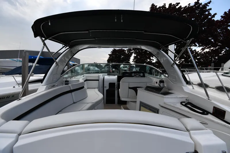  Yacht Photos Pics 2014 Rinker 310 Express Cruiser interior with seating and helm, docked under a canopy.