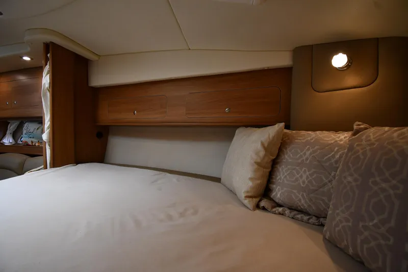  Yacht Photos Pics 2014 Rinker 310 Express Cruiser cabin with cozy bed and wooden storage cabinets.