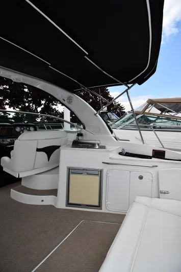  Yacht Photos Pics 2014 Rinker 310 Express Cruiser interior with seating and kitchenette under black canopy.