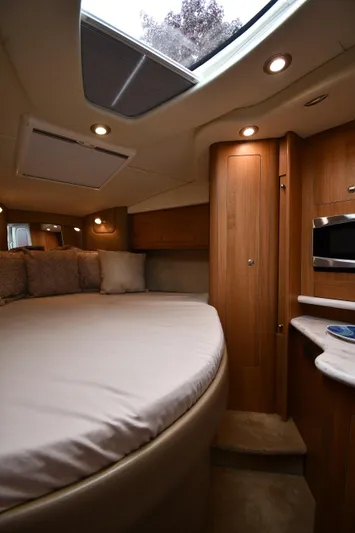 Yacht Photos Pics 2014 Rinker 310 Express Cruiser cabin interior with bed, skylight, and wooden cabinetry.