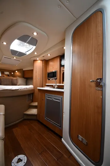  Yacht Photos Pics 2014 Rinker 310 Express Cruiser interior with wood finish, kitchenette, and cozy sleeping area.