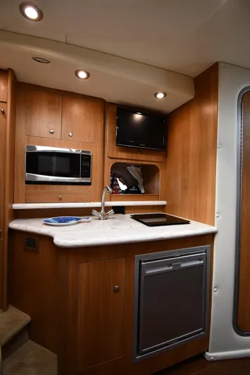  Yacht Photos Pics 2014 Rinker 310 Express Cruiser interior kitchen with microwave, sink, and TV.
