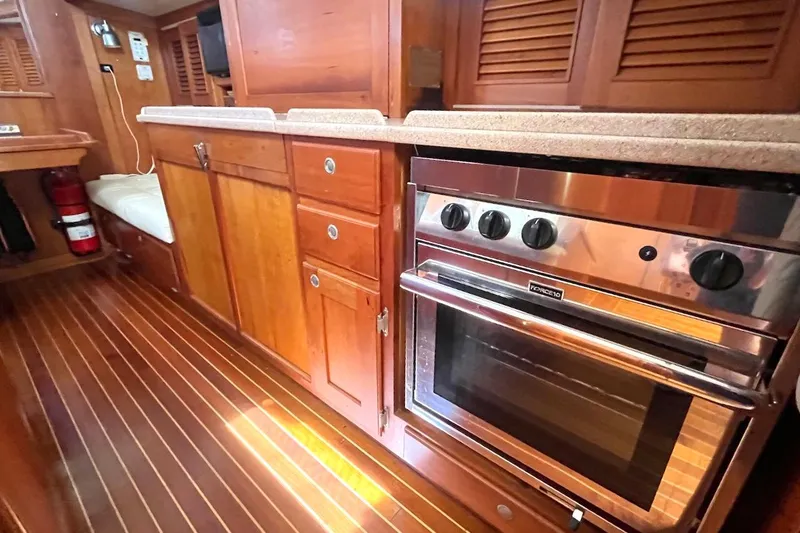  Yacht Photos Pics Wooden yacht interior with stove, cabinets, and striped flooring in a 1997 Gozzard 44.