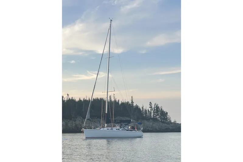 Jane Yacht Photos Pics Sailboat J/120 from 2002 by J Boats, anchored near a forested shoreline.