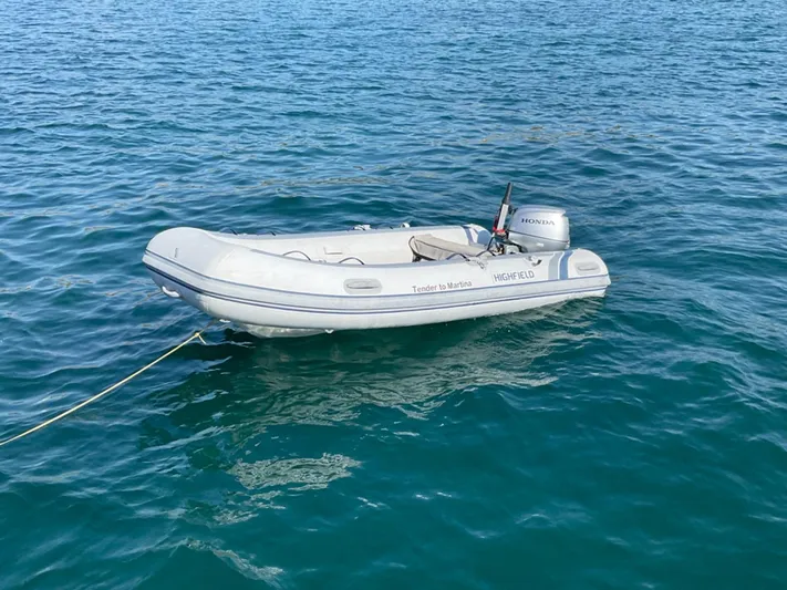Martina Yacht Photos Pics Small inflatable boat with Honda motor floating on clear blue water.