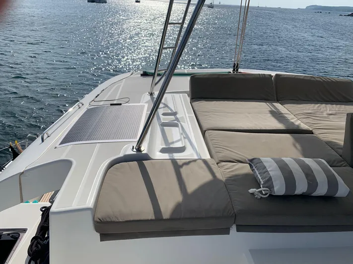 Martina Yacht Photos Pics Luxurious Lagoon 46 catamaran deck with cushioned seating, 2021 model, overlooking serene waters.