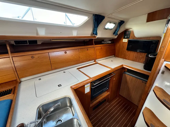 Heeling Alright Yacht Photos Pics Interior of 2001 Jeanneau Sun Odyssey 40 yacht kitchen with wood cabinetry and modern appliances.