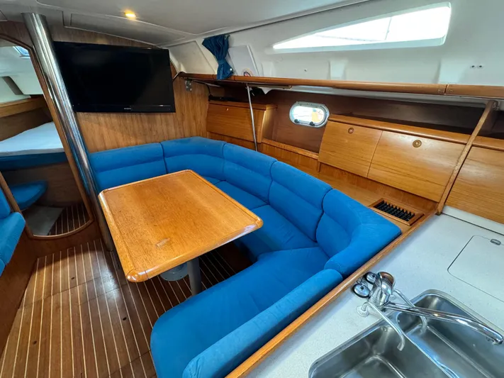Heeling Alright Yacht Photos Pics Interior of 2001 Jeanneau Sun Odyssey 40 sailboat with blue seating and wooden table.