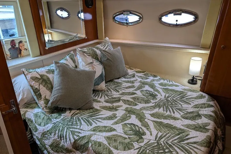 This New Interior Is Amazing! Yacht Photos Pics Cozy bedroom in 2003 Carver 356 Motor Yacht with tropical bedding and porthole windows.