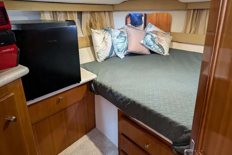This New Interior Is Amazing! Yacht Photos Pics Cozy bedroom in 2003 Carver 356 Motor Yacht with bed, pillows, and mini fridge.