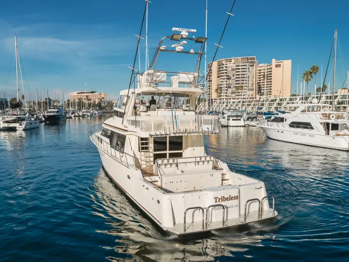 Tribeless Yacht Photos Pics 2002 Mikelson 70 Sportfisher yacht in marina, clear blue sky, surrounded by boats.