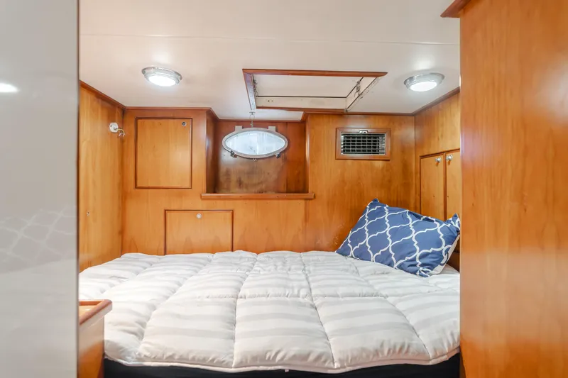 Tribeless Yacht Photos Pics Cozy cabin interior of 2002 Mikelson 70 Sportfisher with wood paneling and bedding.