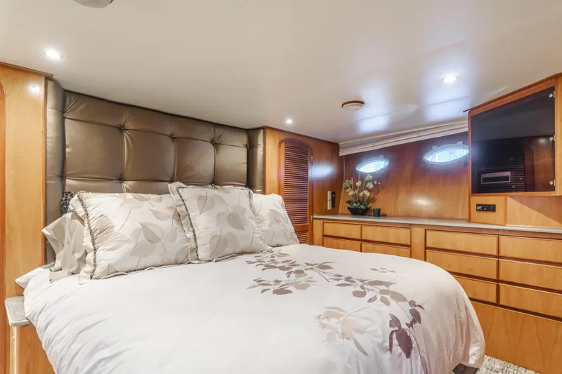 Tribeless Yacht Photos Pics Luxurious bedroom interior of 2002 Mikelson 70 Sportfisher yacht with elegant bedding and wood cabinetry.
