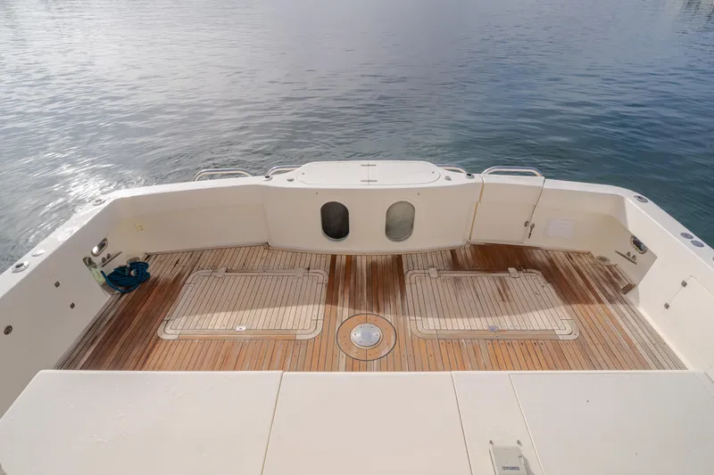 Tribeless Yacht Photos Pics 2002 Mikelson 70 Sportfisher boat deck with wooden flooring, overlooking calm water.