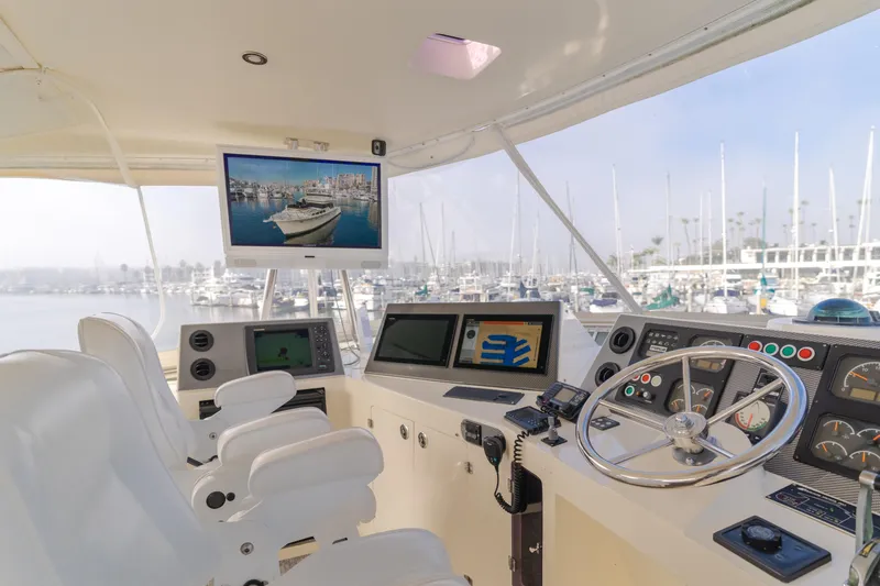 Tribeless Yacht Photos Pics Mikelson 70 Sportfisher 2002 yacht cockpit with navigation screens and marina view.