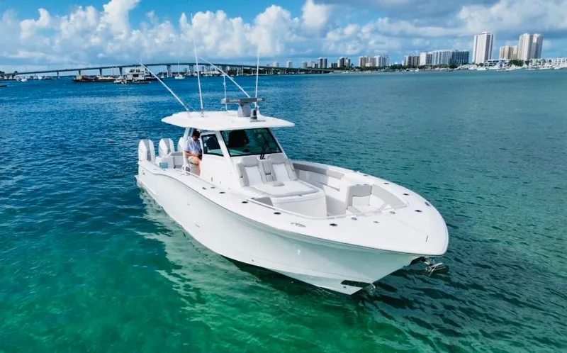  Yacht Photos Pics 2024 Scout 400 LXF boat cruising on clear blue water near a city skyline.
