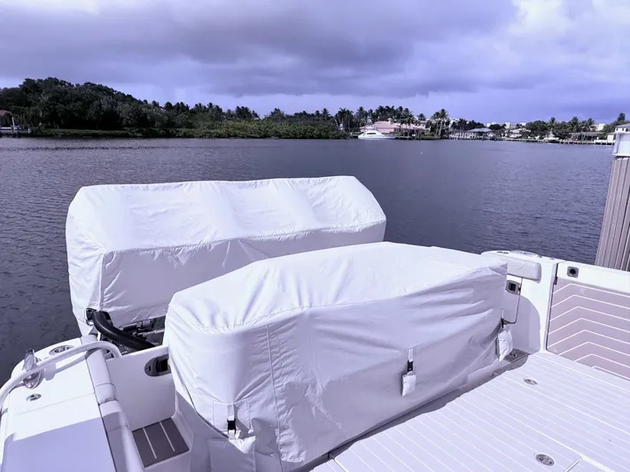  Yacht Photos Pics 2024 Scout 400 LXF boat with covered engines docked by a scenic waterfront.