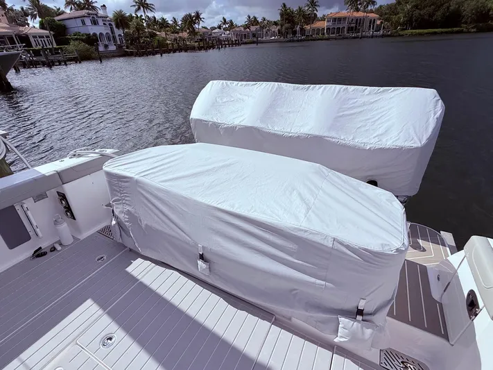  Yacht Photos Pics 2024 Scout 400 LXF boat with covered engines docked by waterfront homes.