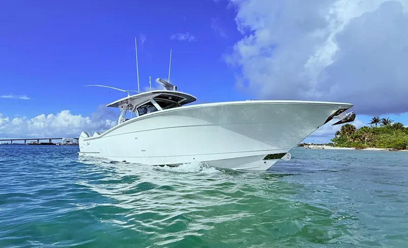  Yacht Photos Pics 2024 Scout 400 LXF boat cruising in clear blue waters under a vibrant sky.