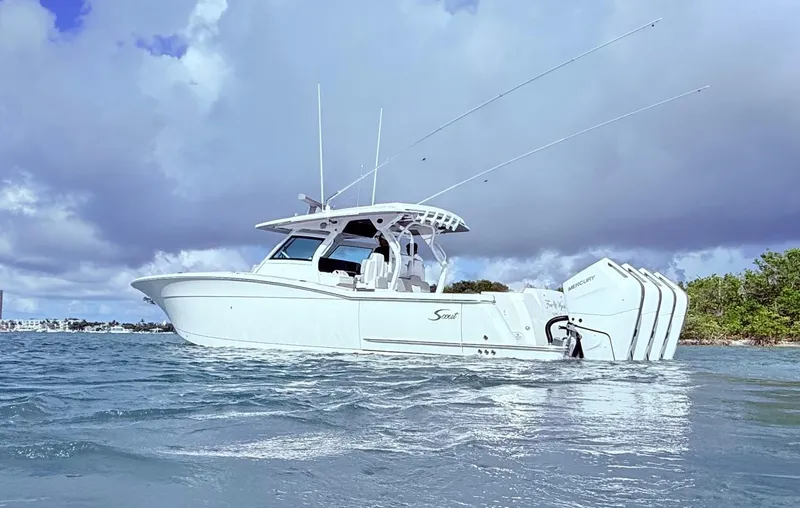  Yacht Photos Pics 2024 Scout 400 LXF boat on water with triple Mercury engines, under cloudy sky.