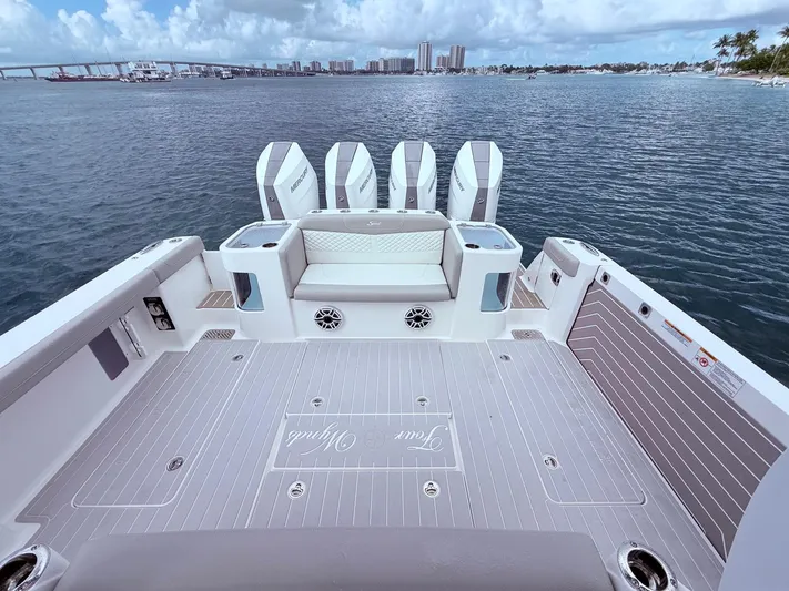  Yacht Photos Pics 2024 Scout 400 LXF boat deck with four engines, overlooking a scenic waterfront.