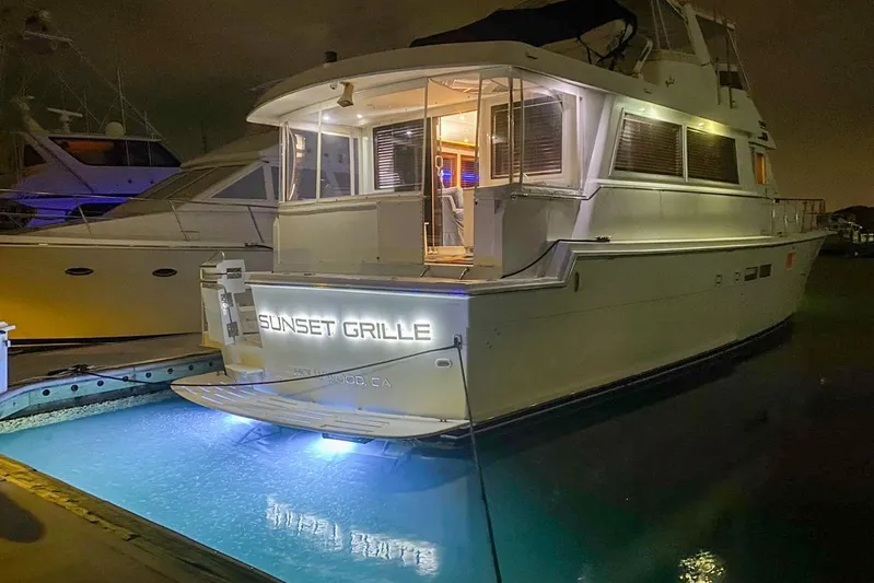 Sunset Grille Yacht Photos Pics 1990 Hatteras 62 Cockpit Motor Yacht docked at night with illuminated nameplate.