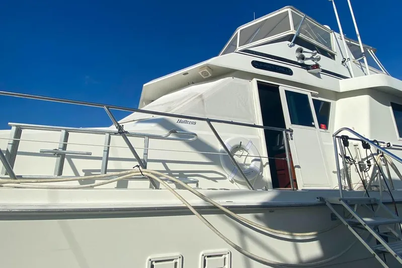 Sunset Grille Yacht Photos Pics 1990 Hatteras 62 Cockpit Motor Yacht with white exterior and railing, under clear blue sky.