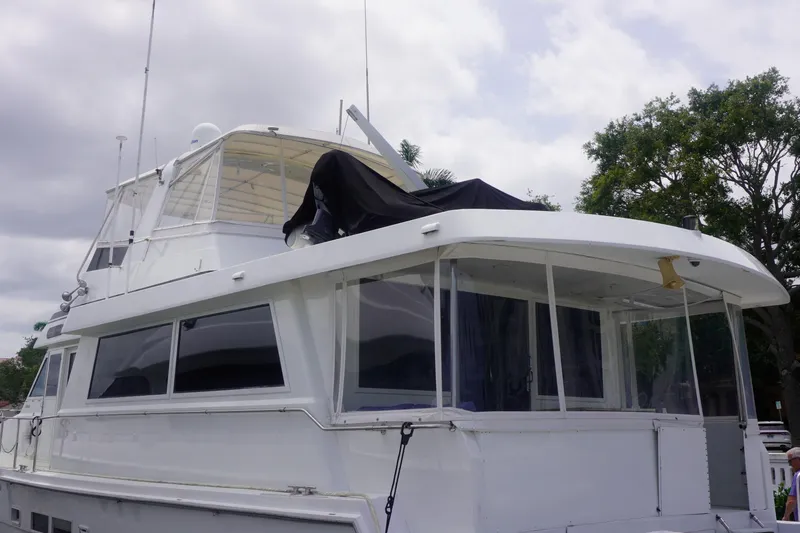 Sunset Grille Yacht Photos Pics 1990 Hatteras 62 Cockpit Motor Yacht with enclosed deck, docked under cloudy skies.