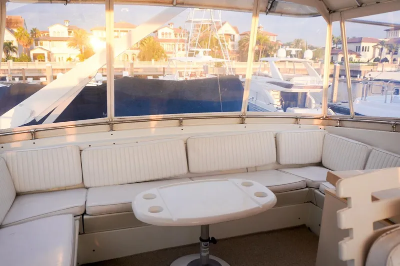 Sunset Grille Yacht Photos Pics Luxurious 1990 Hatteras 62 Cockpit Motor Yacht interior with white seating and marina view.