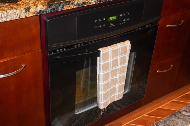 Sunset Grille Yacht Photos Pics Built-in oven with digital display and plaid towel, inside a Hatteras 62 Cockpit Motor Yacht kitchen.