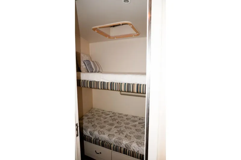 Sunset Grille Yacht Photos Pics Bunk beds in 1990 Hatteras 62 Cockpit Motor Yacht cabin, featuring striped and patterned bedding.