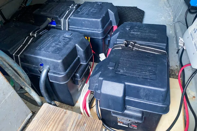 Sunset Grille Yacht Photos Pics Battery compartment of 1990 Hatteras 62 Cockpit Motor Yacht, featuring secured battery boxes.