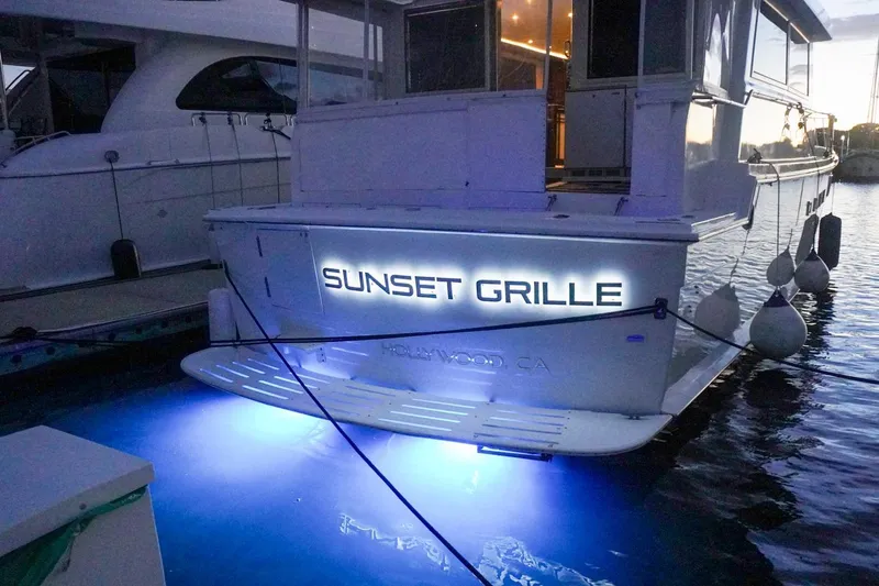 Sunset Grille Yacht Photos Pics 1990 Hatteras 62 Cockpit Motor Yacht docked, illuminated with "Sunset Grille" signage.