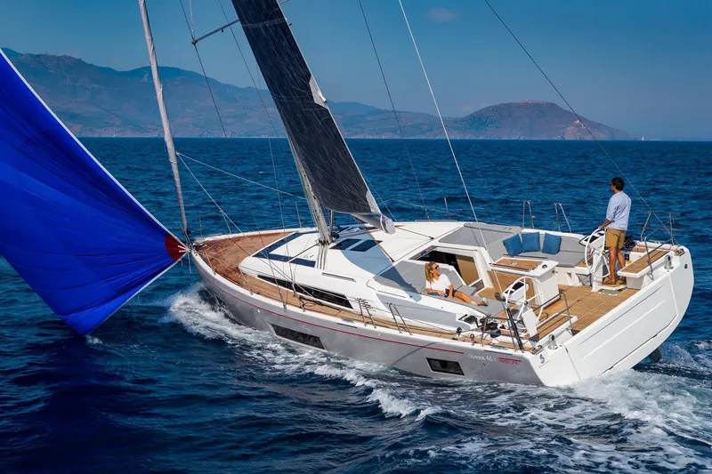  Yacht Photos Pics 2024 Beneteau Oceanis 46.1 sailing on open sea with blue spinnaker sail.