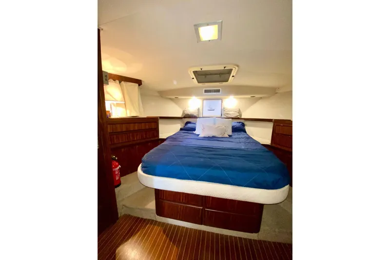  Yacht Photos Pics 1990 Hatteras 41 Convertible yacht bedroom with blue bedding and wooden cabinetry.