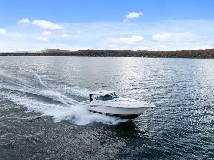  Yacht Photos Pics 2004 Tiara Yachts 3800 Open cruising on a serene lake under a clear blue sky.