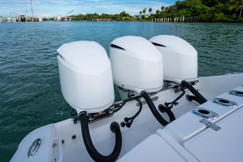  Yacht Photos Pics Triple outboard engines on a 2020 Edgewater 370CC boat, docked on calm water.