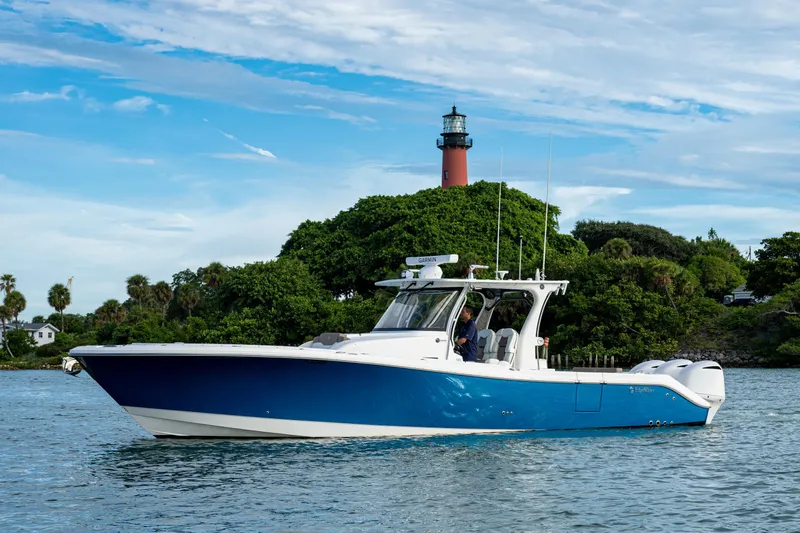  Yacht Photos Pics 2020 Edgewater 370CC boat cruising near a lighthouse under a clear blue sky.