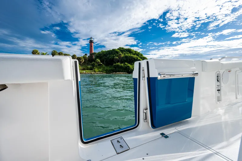  Yacht Photos Pics Edgewater 370CC boat with open door, scenic lighthouse view, blue sky, and water.