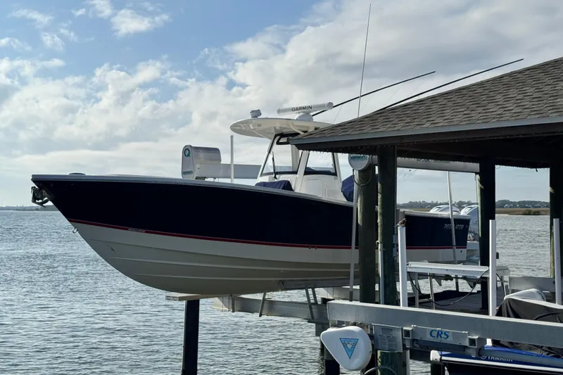  Yacht Photos Pics 2022 Regulator 34 boat docked on a lift by the water under a cloudy sky.