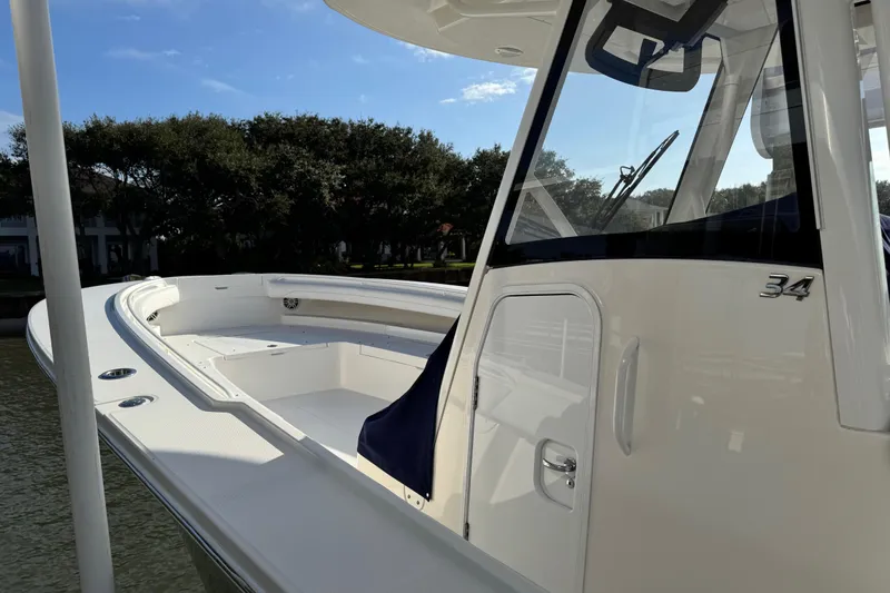  Yacht Photos Pics 2022 Regulator 34 boat with sleek design, docked near trees under blue sky.