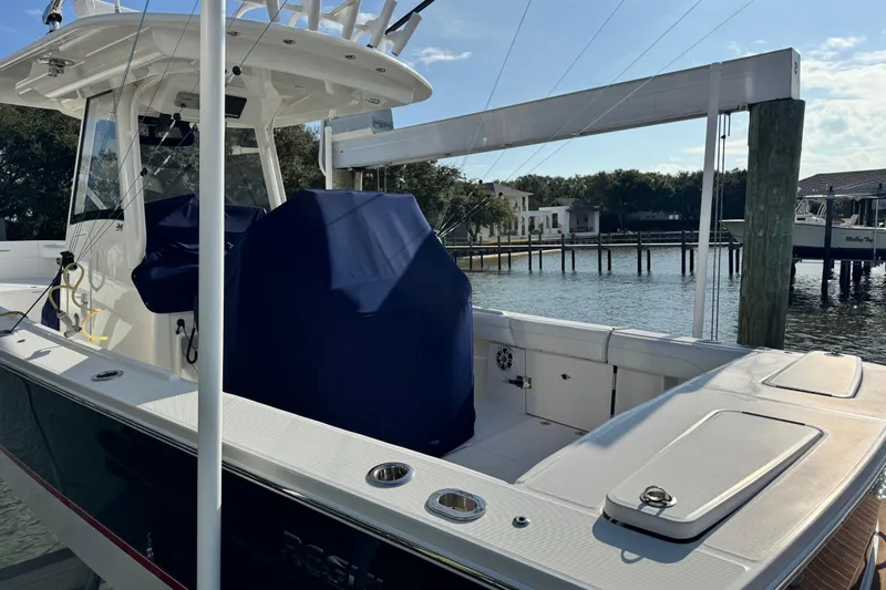  Yacht Photos Pics 2022 Regulator 34 boat docked by waterfront homes, featuring covered seating and fishing equipment.