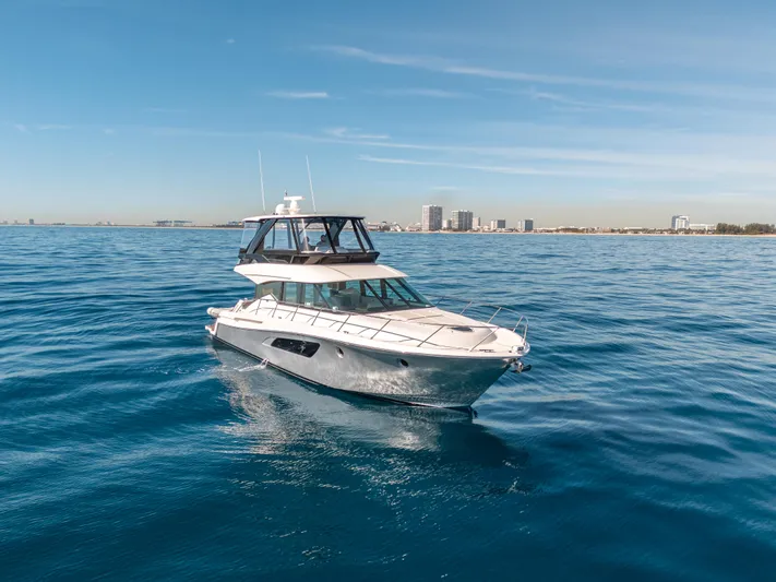 True North Yacht Photos Pics 2017 Tiara Yachts F53 Flybridge cruising on open water, city skyline in background.